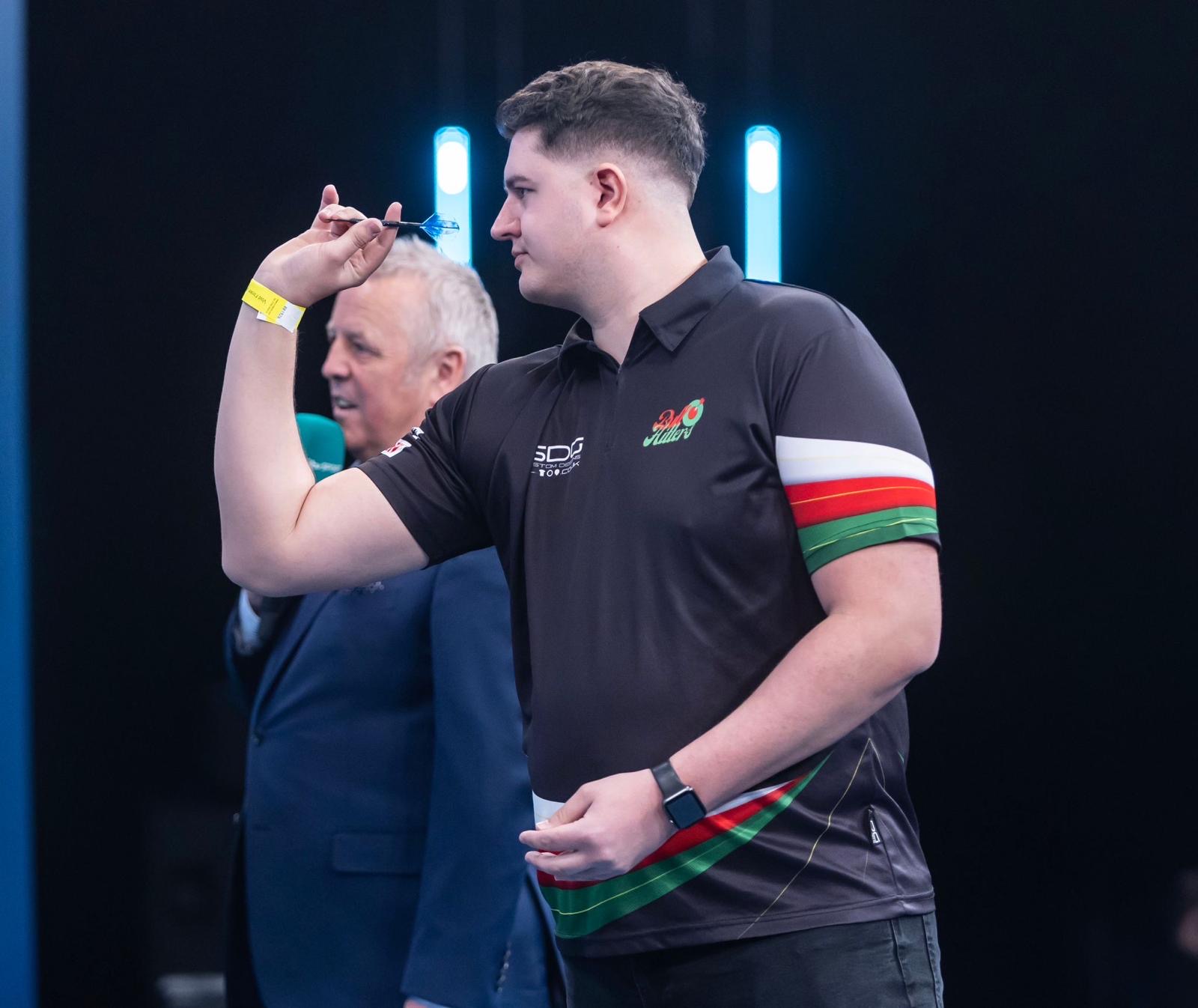 BullHitters creator lining up a dart on stage in side profile